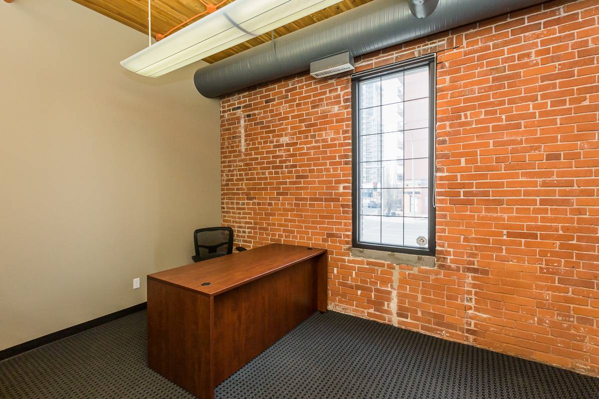 Empty office with brick walls and desk.